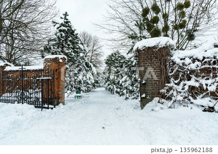 An open gate with a cross towards a snow-covered park with trees, Chelm, Poland An open gate with a cross towards a snow-covered park with trees, Chelm, Poland 135962188