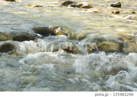 Abstract Water Background in Motion, River Stones Under Clear Flow Abstract Water Background in Motion, River Stones Under Clear Flow 135962206