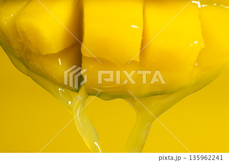 Macro of mango juice dripping from sliced fruit cubes Macro of mango juice dripping from sliced fruit cubes 135962241