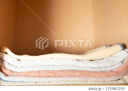 Perfectly folded white and colored towels on wooden shelf for linen closet organization 135962293