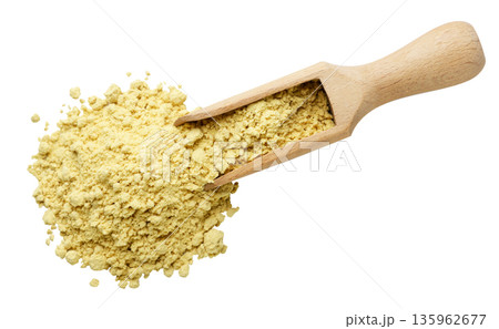 Ground mustard spilling from a wooden scoop on a white. Top view 135962677