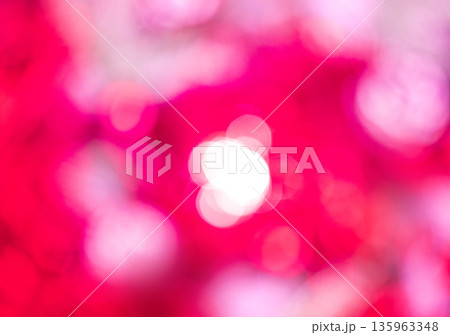 Vibrant pink and white abstract background features bright bokeh light. Numerous soft, blurred circles create a dynamic, energetic visual effect. Christmas or New Years defocused lights backdrop. 135963348