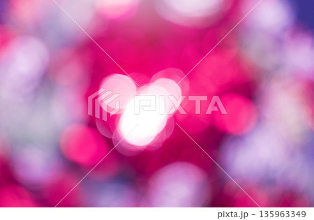 Defocused photography features bokeh effect dominated by pink and magenta colors. Blurred circles of light overlap, with cluster of bright white circles centered in the frame. Abstract background. 135963349