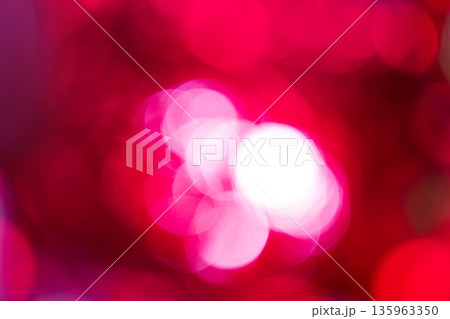 Abstract defocused lights. Blurred circles of white and bright pink light against deep red background, creating dynamic bokeh effect. This soft, defocused view provides colorful, festive atmosphere. 135963350