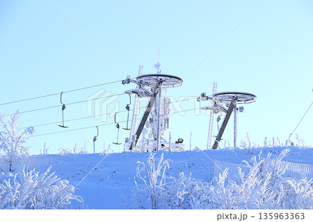 Ski lifts at the Tuutari Park mountain ski resort in the Leningrad region, covered with a thick layer of ice.Winter landscape in central Russia.Beautiful winter invitation card for tourists. Ski lifts at the Tuutari Park mountain ski resort in the Leningrad region, covered with a thick layer of ice.Winter landscape in central Russia.Beautiful winter invitation card for tourists. 135963363