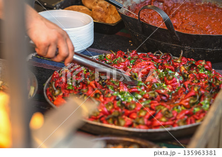 Roasted Red Peppers at Food Counter. Tray of roasted red peppers mixed with herbs and garlic at a food counter. Concept of food preparation, catering, meal service 135963381