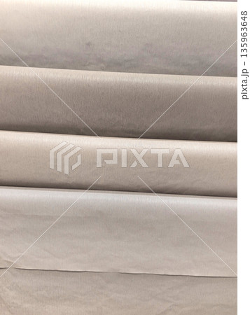 Soft fabric rolls stacked neatly in gentle shades of beige and cream 135963648