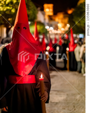 Nazareno holding a lit candle during holy week procession 135963660