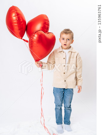 Little boy holding red heart balloons on white background. celebration, love, joy, childhood happiness, studio portrait 135963761