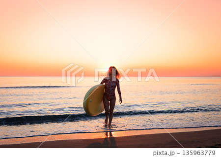 Young woman standing on beach with paddle sup boards during summer vacation 135963779