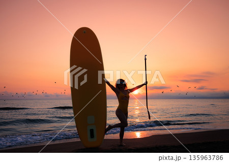 Young woman standing with paddle sup boards by the sea during summer vacation 135963786