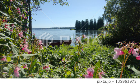 The boat is moored in the water near the forest. 135963975