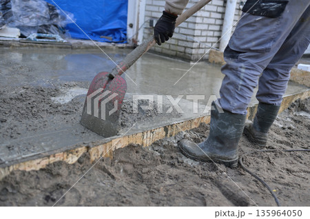 Worker Pouring and Spreading Fresh Concrete Slab in Formwor Worker Pouring and Spreading Fresh Concrete Slab in Formwor 135964050
