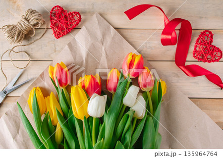 Florist woman wraps large bouquet of multi-colored tulips in eco-friendly craft paper. 135964764