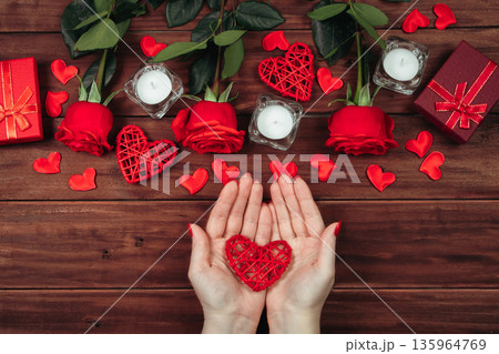 Women's hands hold the heart. Valentine's day concept. Red roses and candles on a wooden background. 135964769