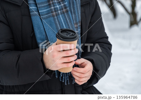 Man holding takeaway coffee cup in winter forest Man holding takeaway coffee cup in winter forest 135964786