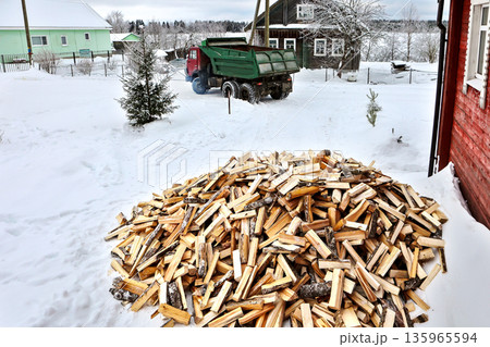 After unloading split logs in front of rural house, firewood delivery truck leaves village. After unloading split logs in front of rural house, firewood delivery truck leaves village. 135965594