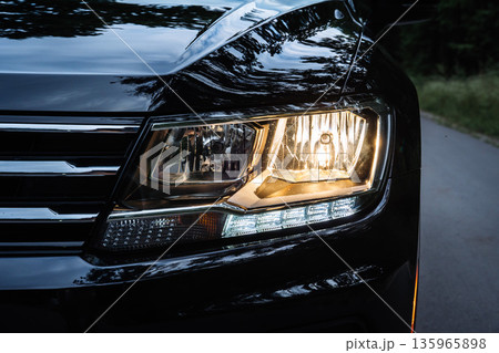 Car Headlight Turned On Close Up on Road at Dusk Car Headlight Turned On Close Up on Road at Dusk 135965898