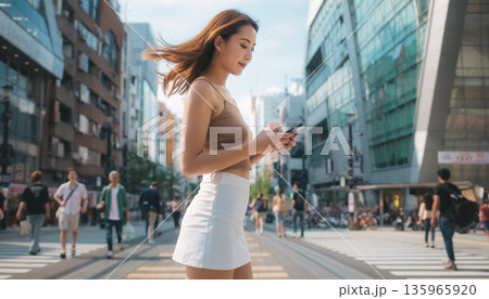 都会の街角でスマートフォンを手に空を見上げて微笑む20代の日本人女性 135965920