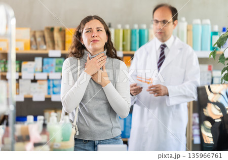 Male pharmacist offering throat pain pills to woman Male pharmacist offering throat pain pills to woman 135966761