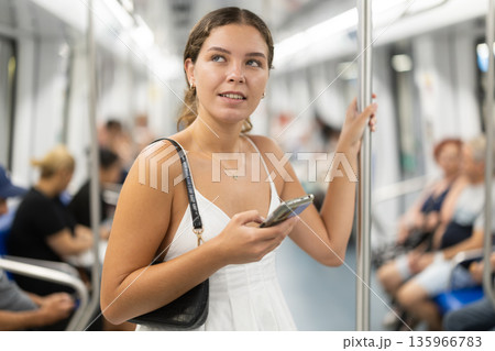 Positive young girl standing on wagon holding phone in hand Positive young girl standing on wagon holding phone in hand 135966783