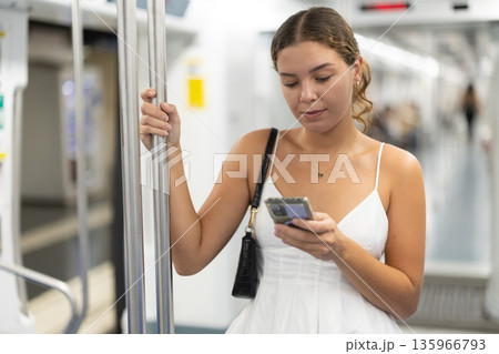 Calm young girl scrolling phone while standing on wagon 135966793