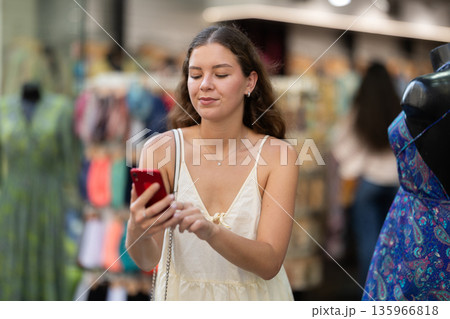 Happy young woman with mobile phone in her hands walking around city and taking pictures of sights Happy young woman with mobile phone in her hands walking around city and taking pictures of sights 135966818