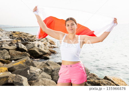 Young woman on coast posing with flag of Poland Young woman on coast posing with flag of Poland 135966876