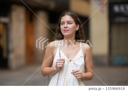 Young woman looks around on city street Young woman looks around on city street 135966918