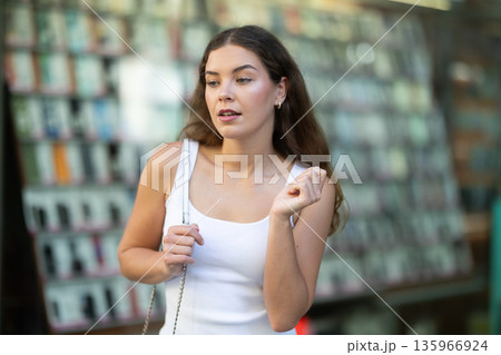 Young girl browsing shop windows while walking in summer city Young girl browsing shop windows while walking in summer city 135966924