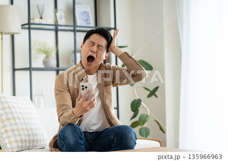 リビングでスマホを使うミドルの男性 リビングでスマホを使うミドルの男性 135966963