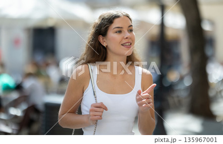 Young smiling girl walks along city street 135967001