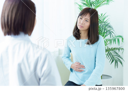 病院で診察を受ける女性　腹痛　体調不良 135967800