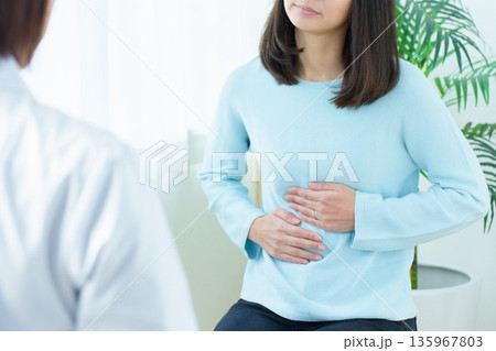 病院で診察を受ける女性　腹痛　体調不良 135967803