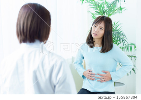 病院で診察を受ける女性　腹痛　体調不良 135967804