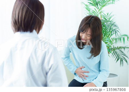 病院で診察を受ける女性　腹痛　体調不良 135967808