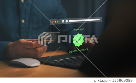 Person holding a credit card and making an online transaction on a laptop, with a digital payment successful message displayed, symbolizing secure online payment, e-commerce, and digital finance. 135969089