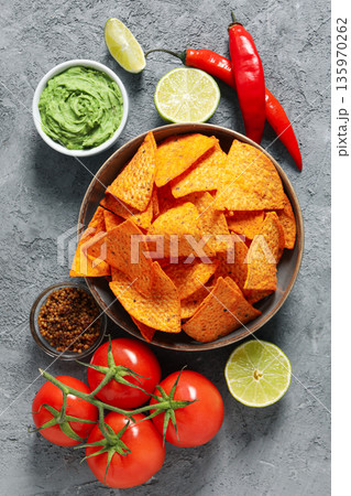 Bowl of tortilla chips with guacamole, tomatoes, and lime slices Bowl of tortilla chips with guacamole, tomatoes, and lime slices 135970262
