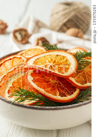 Dried orange slices in a bowl with green plants nearby Dried orange slices in a bowl with green plants nearby 135970263