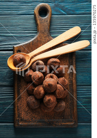 Cocoa balls rest on a wooden board beside two wooden spoons Cocoa balls rest on a wooden board beside two wooden spoons 135970275