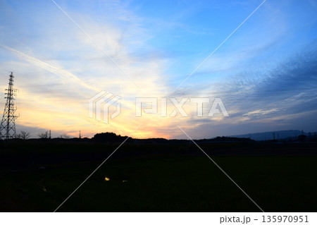 夕焼けに染まった空と鉄塔のイメージ 夕焼けに染まった空と鉄塔のイメージ 135970951