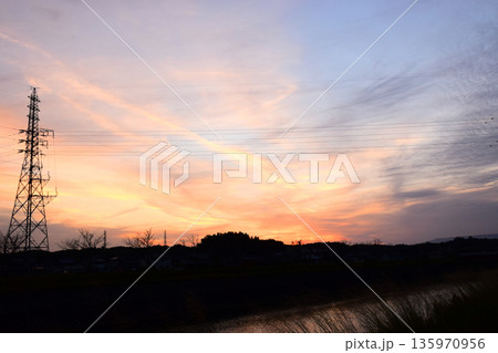 夕焼けに染まった空と鉄塔のイメージ 夕焼けに染まった空と鉄塔のイメージ 135970956