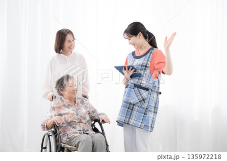 老人ホームや介護施設、看護師と後期高齢者の女性と家族 介護の計画などをタブレットで説明イメージ 老人ホームや介護施設、看護師と後期高齢者の女性と家族 介護の計画などをタブレットで説明イメージ 135972218
