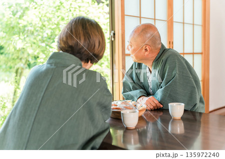 温泉旅行に来て和室でお茶を飲みのんびりするシニア夫婦 135972240