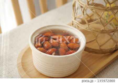 Combination of almonds in a bowl with water on a table Combination of almonds in a bowl with water on a table 135972860