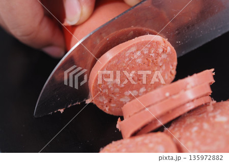Cutting sausage into round slices for a meal Cutting sausage into round slices for a meal 135972882