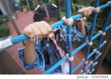 Child climbs on ropes at playground in afternoon light Child climbs on ropes at playground in afternoon light 135972884