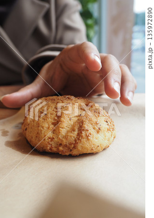 Hand reaches for a baked cookie on a table 135972890
