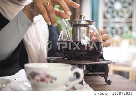 Brewing tea in a glass teapot in a cozy cafe setting Brewing tea in a glass teapot in a cozy cafe setting 135972933