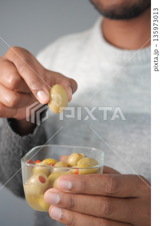 Man picks olives from a clear dish during a snack time Man picks olives from a clear dish during a snack time 135973013